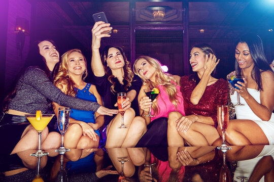 Selfie, club and women with drinks at a party for new year, birthday or festive celebration. Fun, social and friends taking picture on a phone while drinking alcohol beverage in nightclub together.
