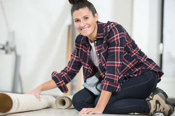 Fototapeta premium happy woman is unrolling a new carpet