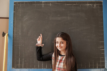 giovane studentessa indica verso una lavagna senza scritte
