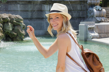 woman holding a coin about to throw it in water