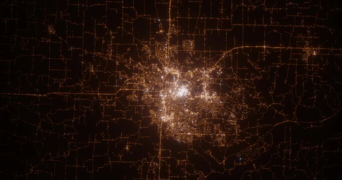 Columbia (Missouri, USA) top view at night. Aerial view on modern city with lights. Camera is flying above the city, moving backward. Vertical video. The north is on the left side