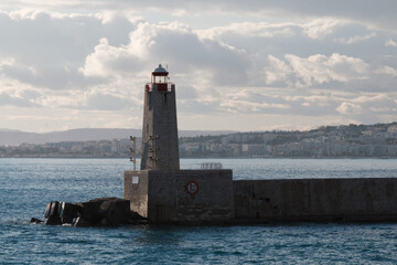 Lighthouse in the port, seascape. Beacon, sea, and clouds at sunset, Nice, France.