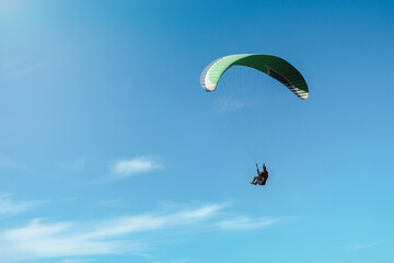 Paraglider flying against the sun on a beautiful sunny day.