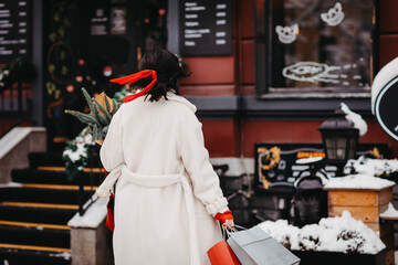 view from back. beautiful brunette on street of winter city with shopping.