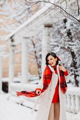an attractive brunette woman in the park of a winter town. 