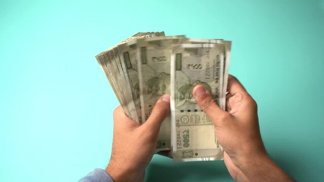 Unrecognizable hand counting five hundred Indian rupees, Close up of hand holding cash.