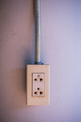 Plastic electric plug on concrete wall with steel tube.