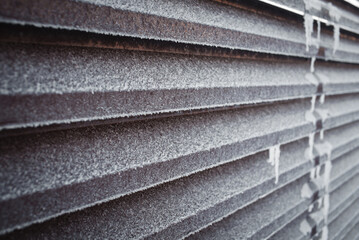 Brown metal fence covered with frost and ice crystals.