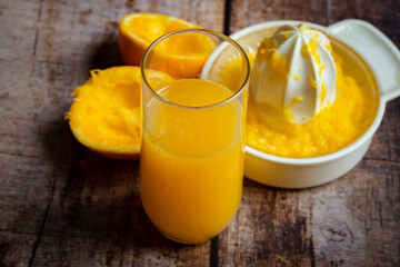 freshly squeezed orange juice in a glass on a wooden background