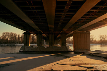 An asphalt road under a steel bridge structure in the city. Night city scene with car lanes.