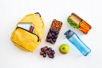 School lunchbox with fruits and yellow backpack, top view