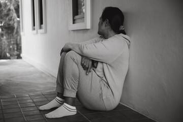 Schizophrenia with lonely and sad in mental health depression concept. Depressed woman sitting against floor at home with dark room feeling miserable. Women are depressed, fearful and unhappy.