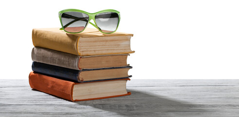 Stack of colored books and sunglasses on the desk