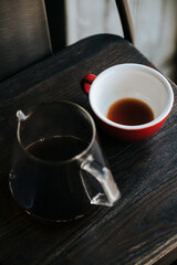 Black coffee in glass teapot and red cup