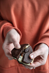 Girl holds broken chocolate cookie. Whoopie pie