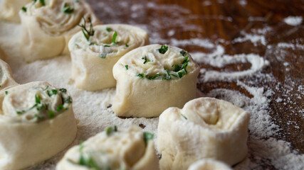 Raw pastry. Dough. The pastry is sprinkled with greens. Dough rolls.