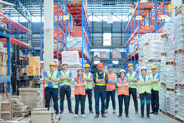 Obraz premium Smiling warehouse team with arms crossed in a large warehouse ,Logistics industry concept.