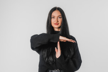 Young woman showing time out hand gesture to stop something, standing over white background. Human...