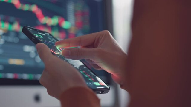 Closeup - Woman is checking Bitcoin price chart on digital exchange on smartphone, cryptocurrency future price action prediction.