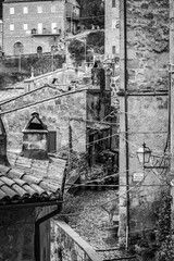 Black and white vertical cityscape, town of Sorano, Tuscany, Italy. Moody late autumn travel perspective. 