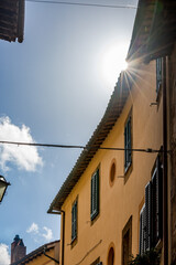 Fototapeta na wymiar Narrow street in the town of Sorano, Tuscany, Italy. Moody late autumn travel perspective. Sun light diffraction effect.