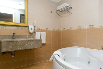 Large semi-circular white bathtub installed corner of the room.