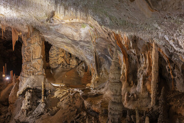 A wall with columns and lace in the Postojna cave. The white spots is reflected light in water droplets