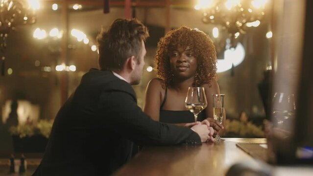 couple dating in bar of luxury restaurant in evening, drinking wine and flirting, first date