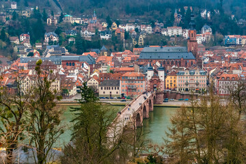 Fototapeta na wymiar Picturesque view of the old town centre of Heidelberg, Germany, with the bridge Karl-Theodor-Brücke including the famous bridge gate Brückentor and behind stands the church Heiliggeistkirche.