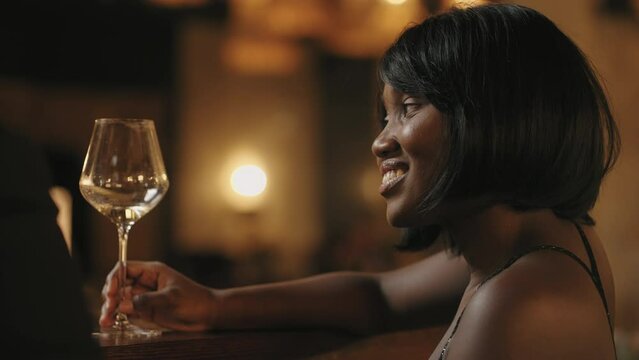 portrait of beautiful young black woman in bar, drinking wine and flirting with man