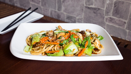 Asian combo plate with chicken and vegetables served with noddles.