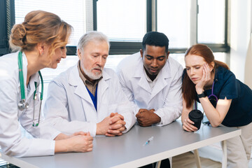 Pensive medical team multi-ethnic professional doctors discussing new coronavirus vaccine standing...