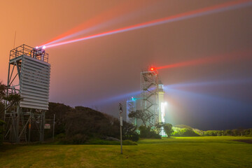 Beams of light from a lighthouse and beacon tower on a dark foggy night