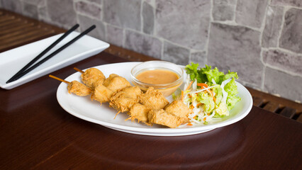 Skewers with battered chicken and peanut sauce. Traditional Asian recipe.
