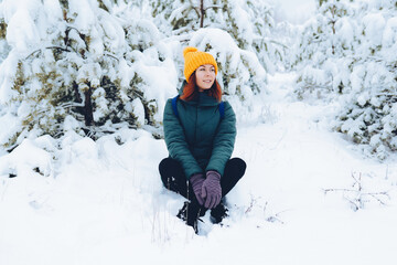 Fototapeta na wymiar Cheerful girl in warm clothes playing with snow outdoors near the beautiful forest