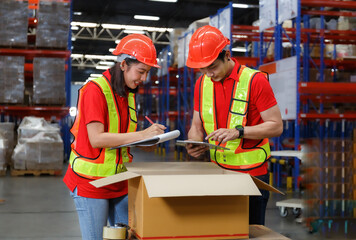 Asian male and female workers in safety suits wear hard hats. pack the product into a box