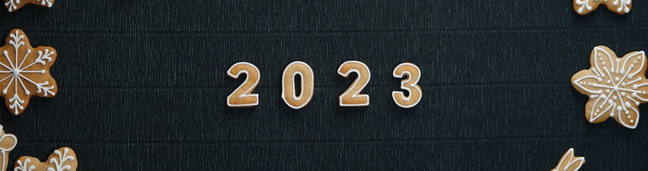 Christmas Border of glazed cookies with date 2023 inside on a Dark background. View from above. Happy New Year. Wide Photo