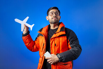 Journey, airplane ticket, vacation. One man showing a paper cut airplane isolated on blue background