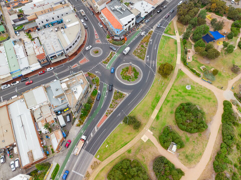 Aerial view of roads and roundabouts running through a shopping strip and parkland