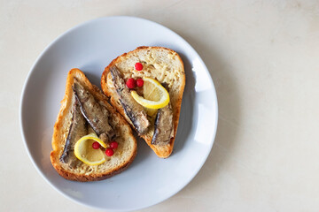 Sandwiches with sprats, a slice of lemon and lingonberries.