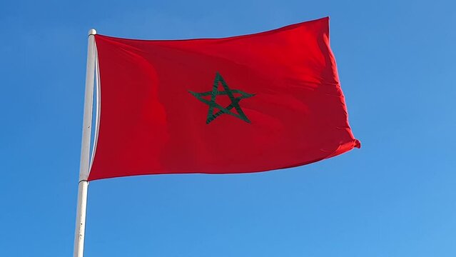 low angle view of the Moroccan flag waving against blue sky