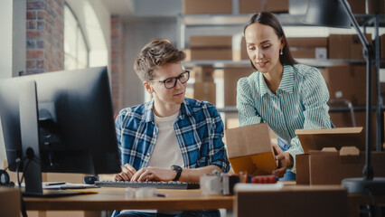 Small Business Owners Using Desktop Computer, Preparing a Small Parcel for Shipping in a Storeroom. Young Man and Woman Working in Warehouse, Preparing Online Orders for Clients.