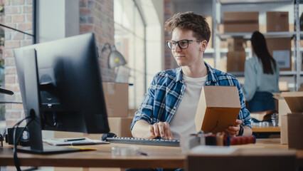 Small Business Owner Checks Stock and Inventory on Desktop Computer in the Retail Warehouse full of Shelves with Goods. Working in Logistics, Distribution Center with Female Colleague.