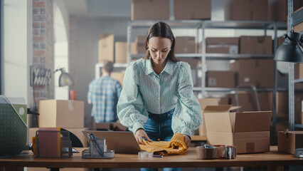 Small Business Owner of an Online Store Works on Laptop Computer while Leaning On Her Desk in...