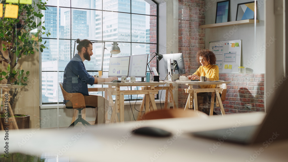 Poster two specialists sitting behind desks next to big window with downtown city view and work with report
