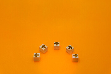 中央から多方向を指す5個の矢印のウッドキューブのオレンジ色の背景