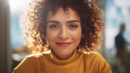 Close Up Portrait of a Young Middle Eastern Woman with Short Curly Hair, Looking for Camera, Wearing a Yellow Sweater. Beautiful Diverse Multiethnic Female Wearing Yellow Smiling and Being Happy.