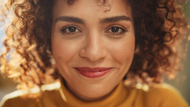 Close Up Portrait of a Young Middle Eastern Woman with Short Curly Hair, Looking for Camera, Wearing a Yellow Sweater. Beautiful Diverse Multiethnic Female Wearing Yellow Smiling and Being Happy.