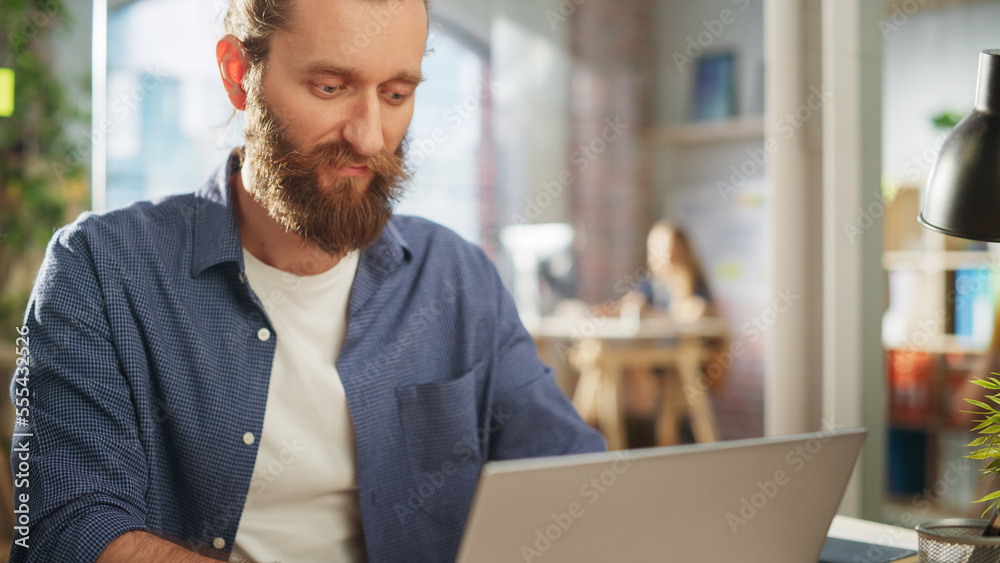 Poster close up portrait of a handsome long-haired bearded manager sitting at a desk in creative office. st
