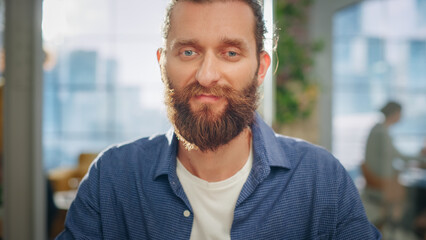 Fototapeta premium Portrait of a Handsome Man in Creative Agency. Young Stylish Manager with Long Hair and a Beard Looking at Camera. Successful Manager Working in Modern Company.